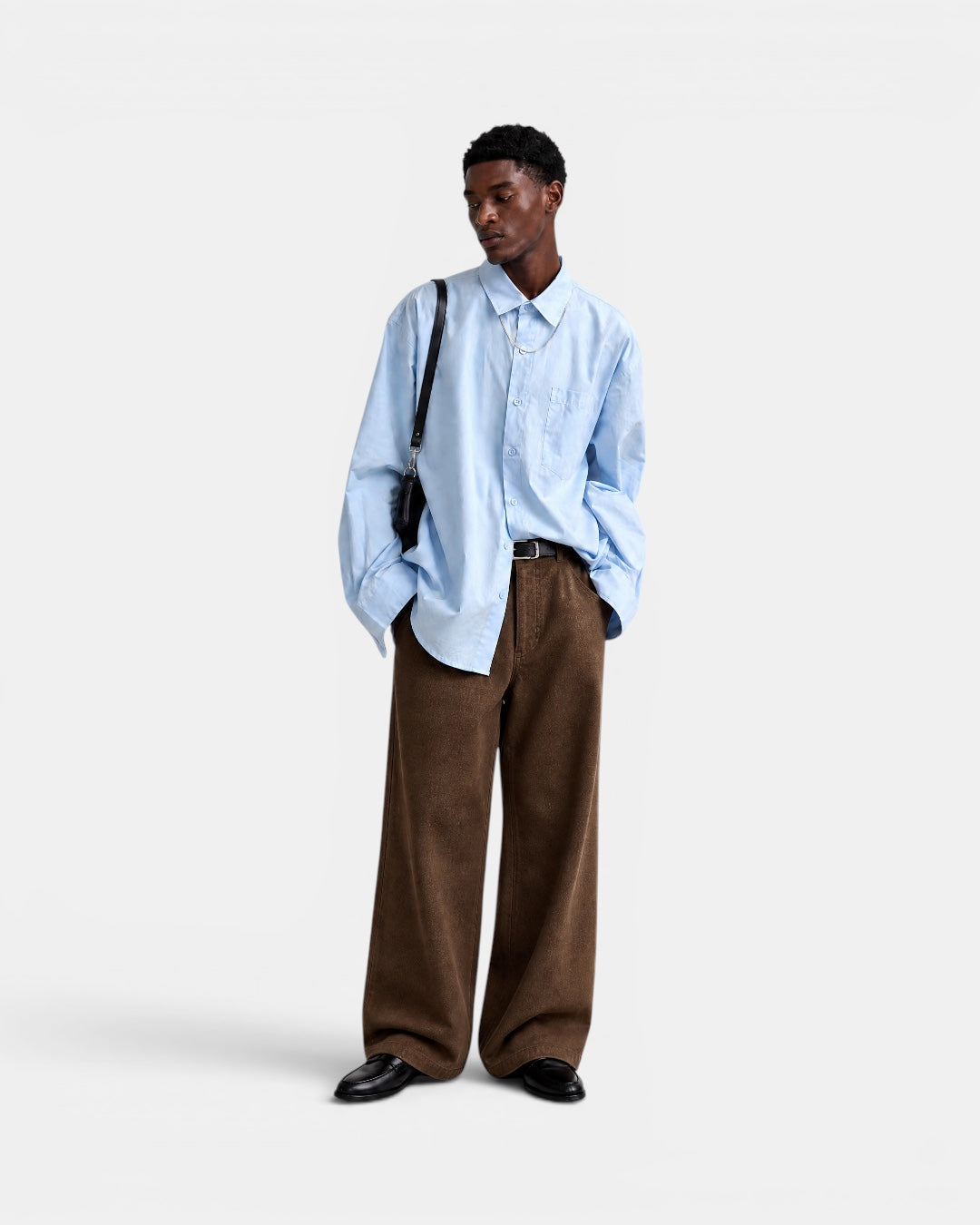 Nameless light blue solid-color long-sleeved cotton shirt worn by a man with brown corduroy pants and black loafers.