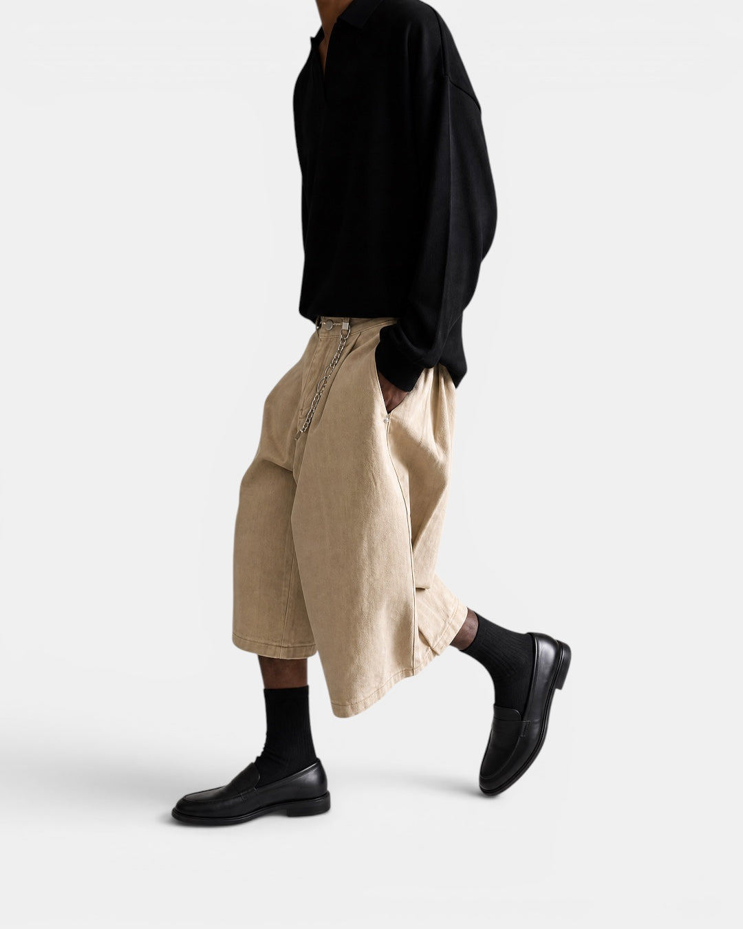 Nameless beige three-dimensional tailored wide-leg shorts with chain detail, worn by a model with a black collared shirt and black loafers.