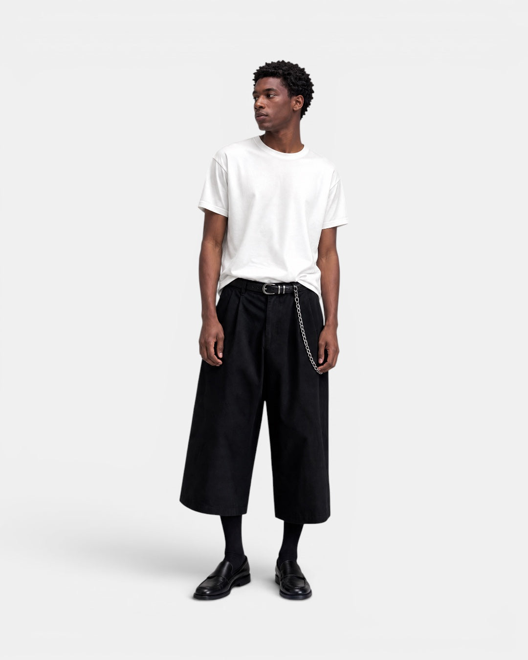 NAMELESS black wide-leg culotte shorts with chain detail, worn by a man with a white t-shirt and black loafers.