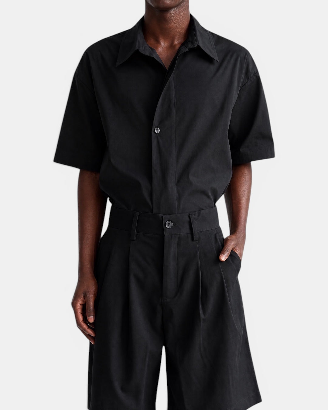 NAMELESS black short-sleeved cotton shirt with pointed collar and slanted placket, worn by a man.