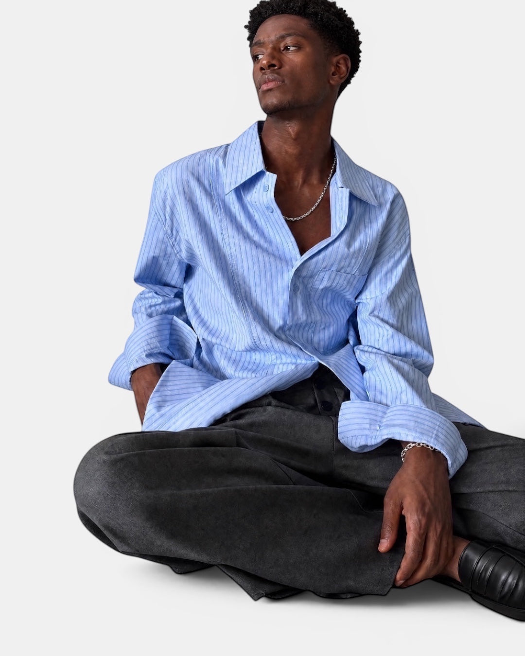Nameless light blue fine-textured striped long-sleeved shirt worn by a man sitting.