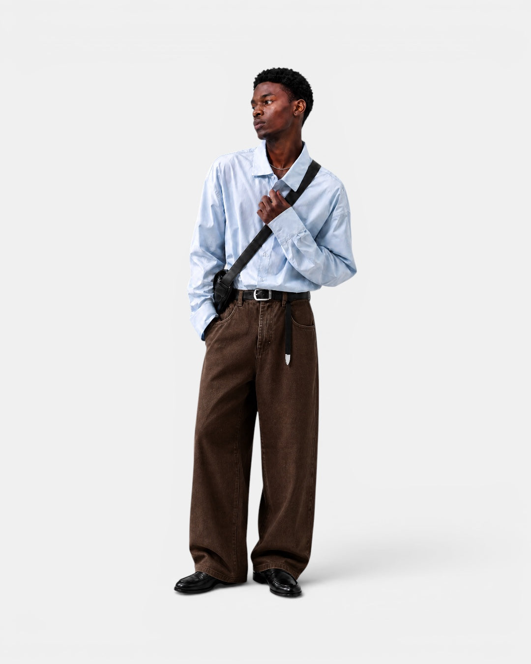 Nameless light blue solid-color long-sleeved cotton shirt worn by a man with brown wide-leg jeans and black loafers.