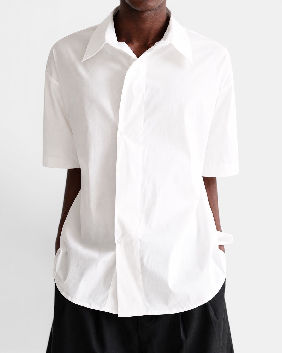 Nameless white cotton short-sleeved shirt with pointed collar and slanted placket, worn by a model.