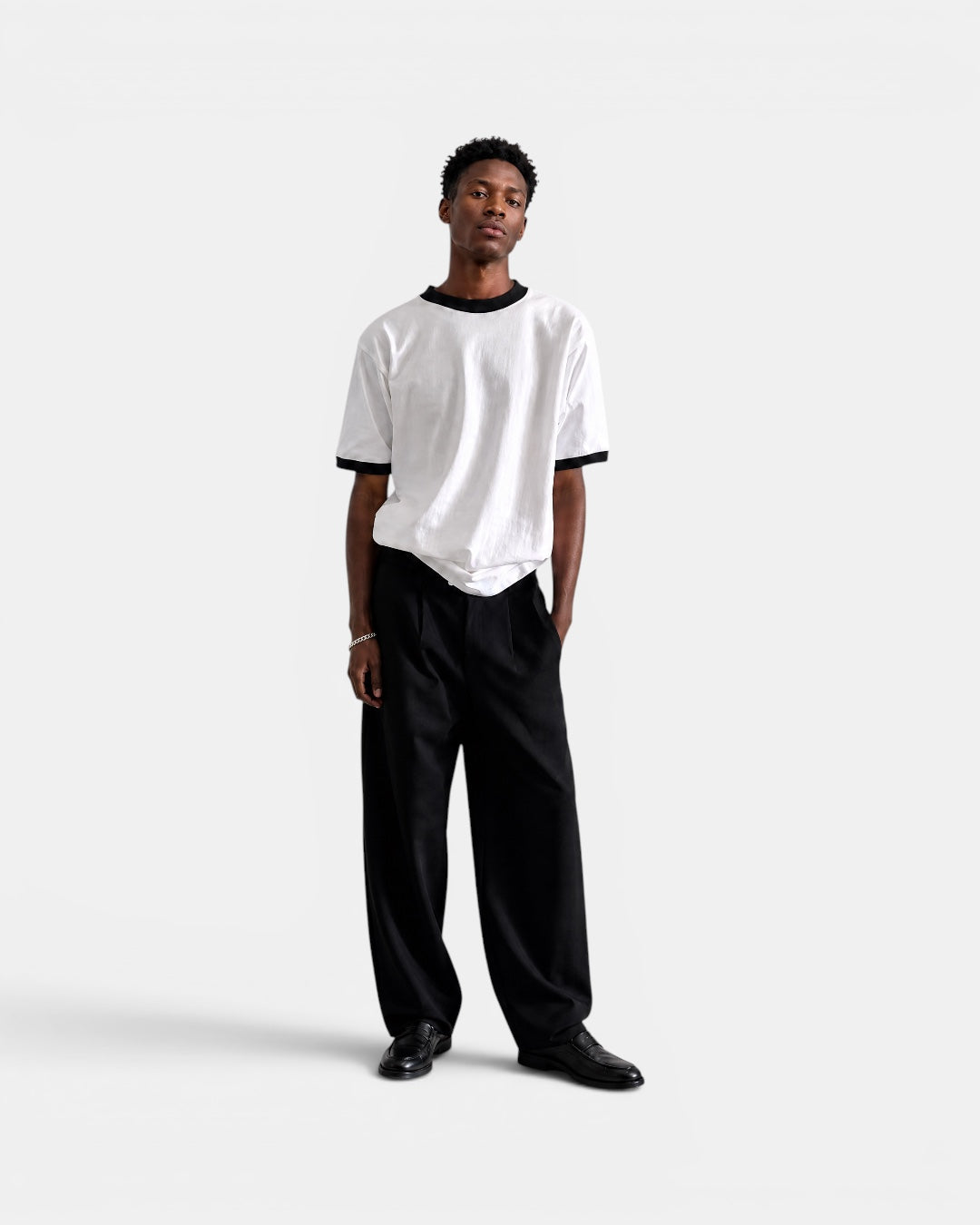 Nameless white cotton t-shirt with black trim on collar and sleeves, worn by a man with black pants.