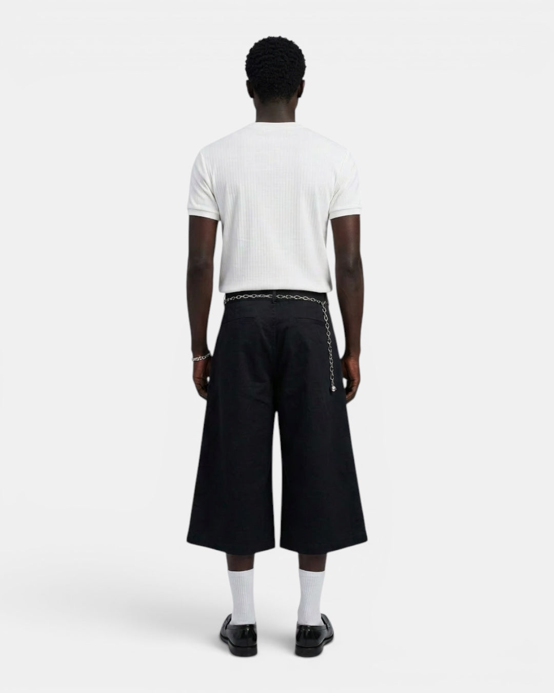 NAMELESS white ribbed short-sleeve t-shirt with a Henry collar, paired with black wide-leg culottes and a silver chain belt.