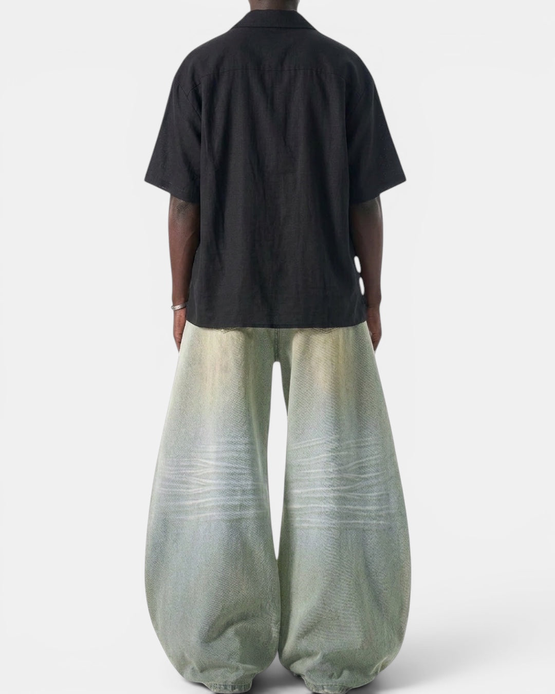 NAMELESS light wash wide leg denim jeans with a curved silhouette and vintage wash details. Model wears black short-sleeve shirt.